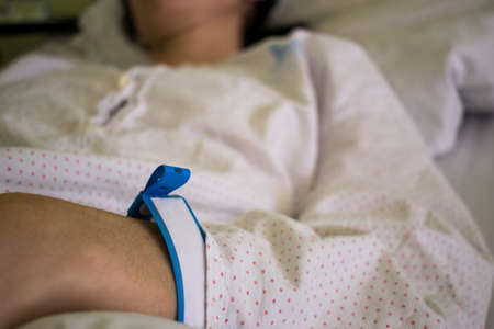 A hand of female patient with hospital bracelet while hospitalized and recovery. Close up.