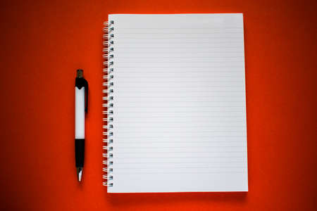Notepad with black and white pen on orange backgroundの写真素材