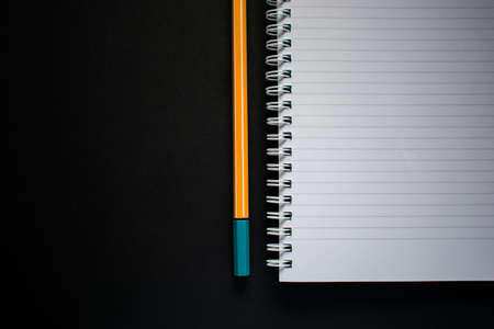 Cut out of flat lay yellow pen and notepad on black backgroundの写真素材