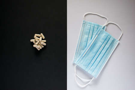 Medical pills and blue medical mask on black and white backgroundの写真素材