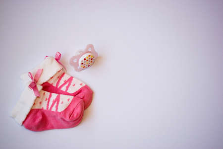 Small newborn baby girls pink socks and pacifier on white backgroundの写真素材