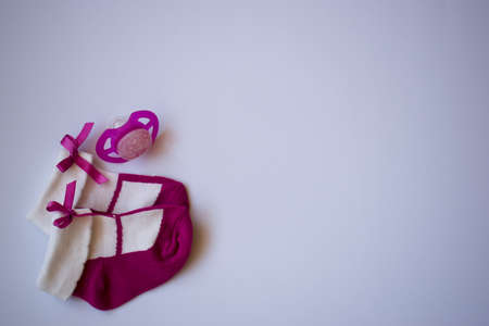 Purple newborn baby girls socks and pacifier on white background