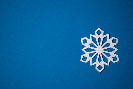 White paper cut snowflake on blue backgroundの写真素材