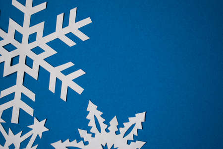 White paper handmade snowflakes on blue colored paper backgroundの写真素材