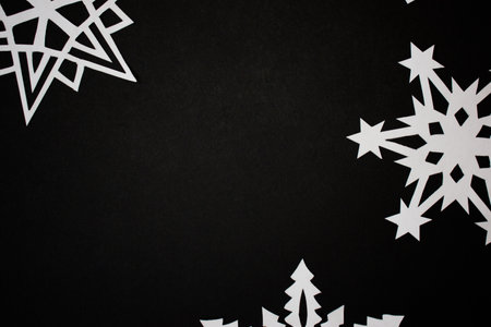 Paper handmade cut out snowflakes on black background
