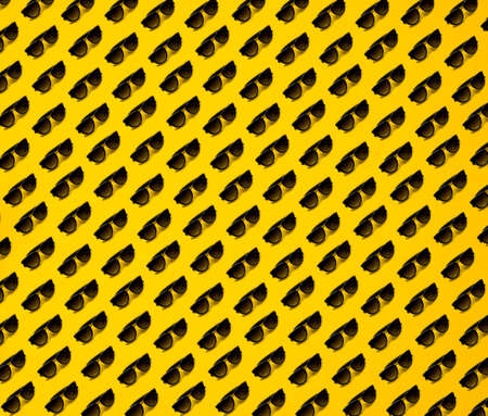 Black sunglasses pattern on yellow background. Summer conceptの写真素材