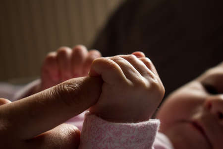 Newborn baby holding mothers finger. Concept of love and familyの写真素材