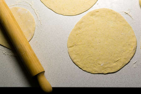 Top view of wooden rolling pin and dough for tortillas on white working surfaceの写真素材