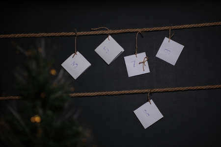 homemade DIY advent calendar, created on a black background and tied with a craft string, in the foreground is a Christmas tree with a garlandの写真素材