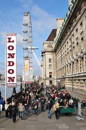 LONDON, UK - MARCH 8, 2011: Crowds of tourists with the London Eye overlooking the Thames riverのeditorial素材