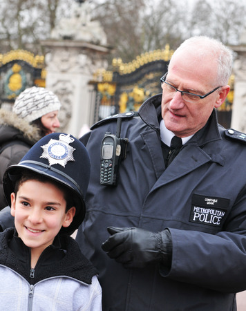 LONDON, UK - MARCH 5, 2011: London local Metropolitan policeman in uniform gives his hat to a touristのeditorial素材