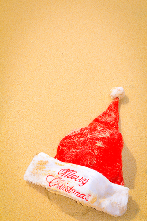 Santa hat washed by waves on the beachの写真素材