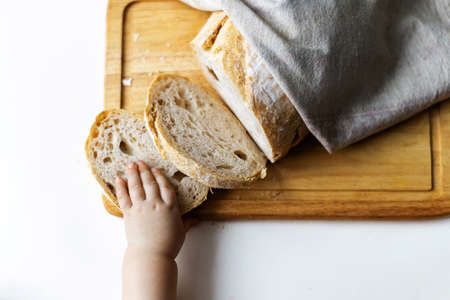 Close up of child's hand picks up a piece of bread