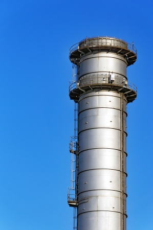 metallic smokestack with stairs against blue skyの写真素材