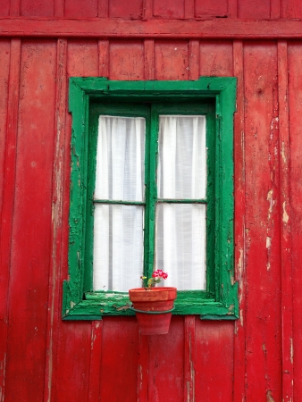 old window on an aged wooden facade with flowerpotの写真素材