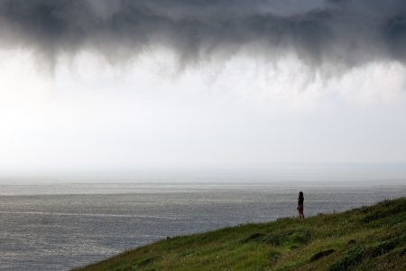person looking at sea with stormy cloudsの写真素材