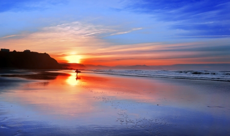 surfer in the beach at sunset with beautiful reflectionsの写真素材