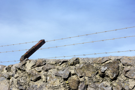 fence with barbed wire against blue skyの写真素材
