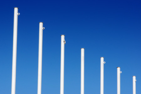 empty white flag poles against blue skyの写真素材