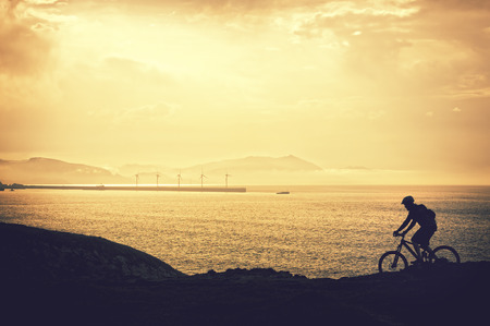 biker silhouette riding on cliffの写真素材