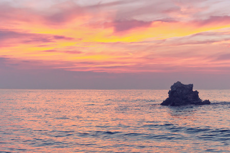 rock at sunset on the sea with pink colorsの写真素材