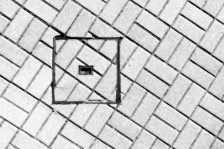 abstraction of steel sewer manhole on floor with cobblestone