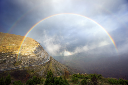 mountain pass road with stormy clouds and a rainbowの写真素材