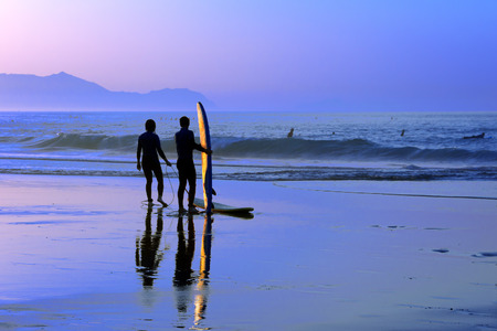 surfers with sunset reflection on the surfboardの写真素材