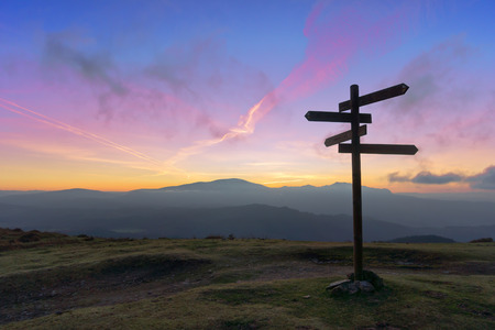wooden signpost on mountain at sunsetの写真素材