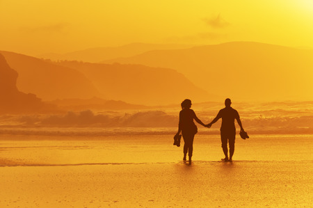 couple walking on beach at the sunsetの写真素材