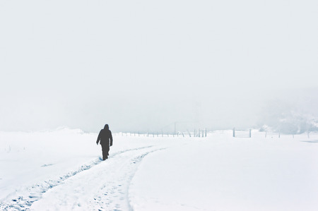 person walking alone on snowy winter landscapeの写真素材