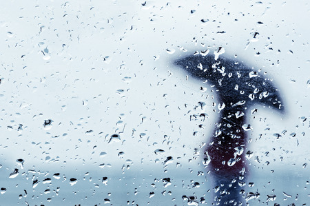 raindrops on window with person with umbrellaの写真素材