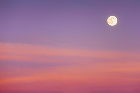 full moon with red sunset cloudsの写真素材