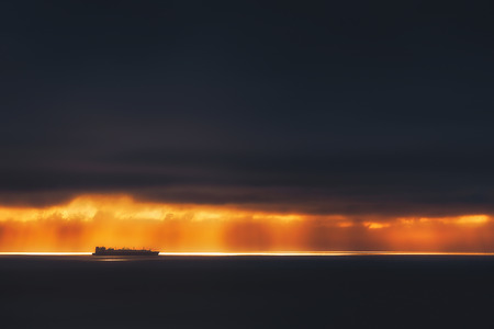 sunrays on the ocean with freighter shipの写真素材
