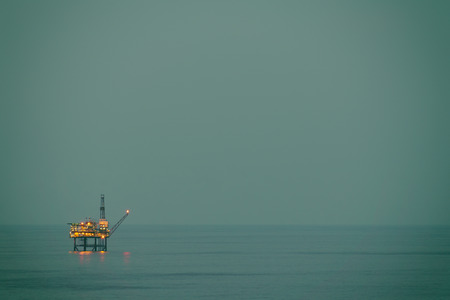 oil rig drilling platform over sea at nightの写真素材