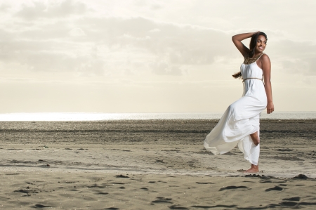 An african girl doing a dance pose with a smile at the beachの写真素材