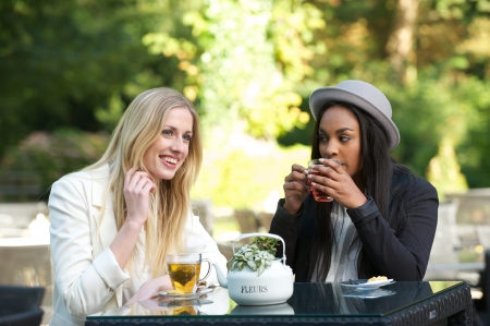multicultural friends drinking tea and laughing outdoorsの写真素材