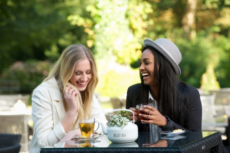 two girls drinking tea and laughing outdoorsの写真素材