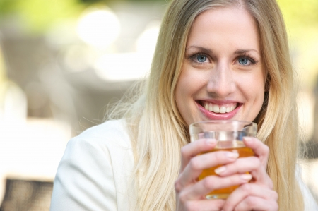 A Blonde Girl is Holding her Tea Cup to her Mouthの写真素材