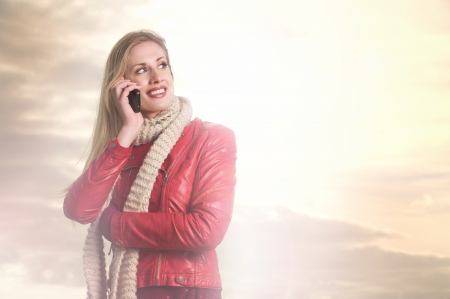 Young Blond Girl is Making a Call on her Mobile Phoneの写真素材