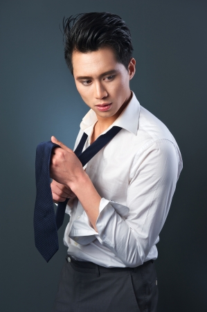 Portrait of a handsome Asian businessman adjusting  grey tieの写真素材