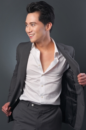 Handsome fashion businnessman posing  in studio. He is smiling and holding his suit jacket open.の写真素材