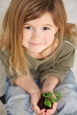 Close up portrait of a child holding plant growing from soil in handsの写真素材