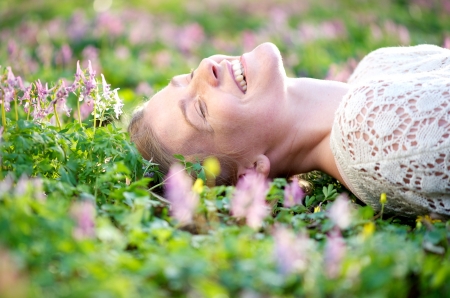 Happy young female lying on a flower fieldの写真素材