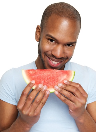 Close up portrait of a handsome young man smiling and eating delicious watermelonの写真素材