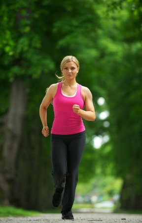 Portrait of an active female runner in sportswear jogging in the park の写真素材