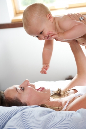 Portrait of a woman and baby playing in bedの写真素材