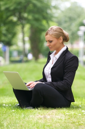 Portrait of a beautiful business woman sitting with laptop in parkの写真素材