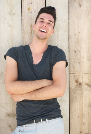 Closeup portrait of an attractive young man laughing with arms crossedの写真素材