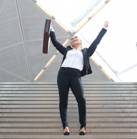 Portrait of a businesswoman celebrating arms outstretched on staircaseの写真素材